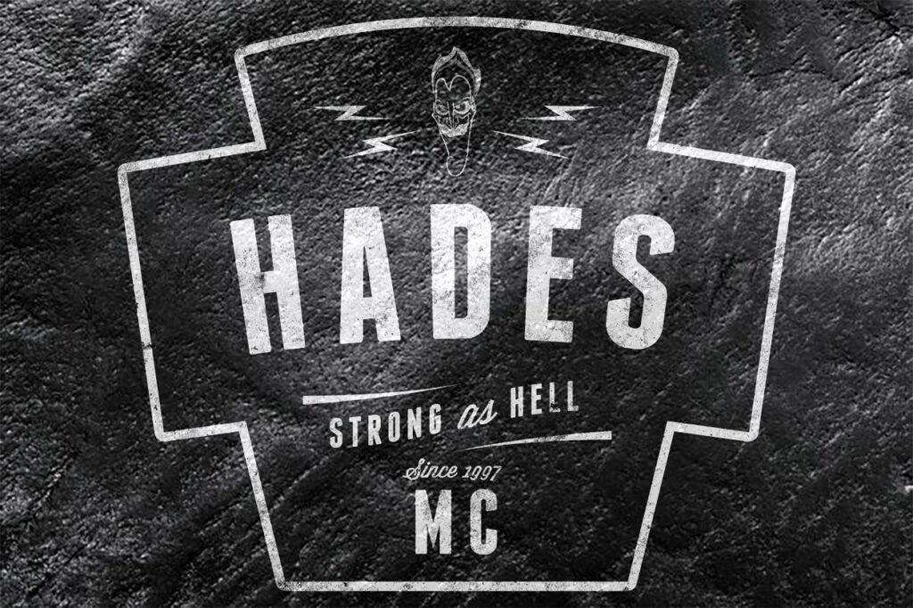 Leather jacket with a "motorcycle club" logo painted on with text "HADES MC. STRONG AS HELL SINCE 1997"